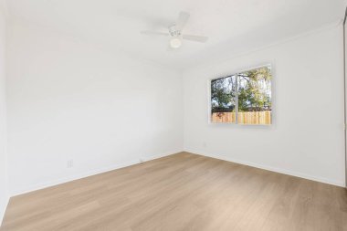 Beyaz duvarları ve ahşap zemini olan boş bir oda.