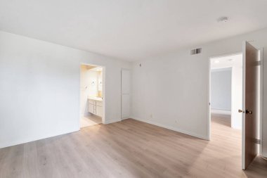 Beyaz duvarları ve ahşap zemini olan boş bir oda.