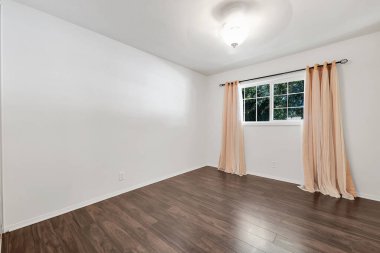 Beyaz duvarları ve ahşap zemini olan boş bir oda.