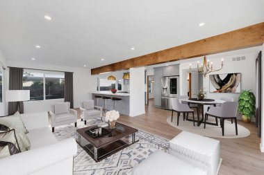 Modern oturma odasının içinde beyaz kanepe ve sandalyeler var.