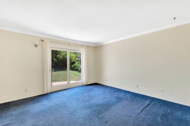 Beyaz duvarları ve zemin halısı olan boş bir oda