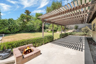 Evin arka bahçesi, yeşil çimenlik ve şömineli.