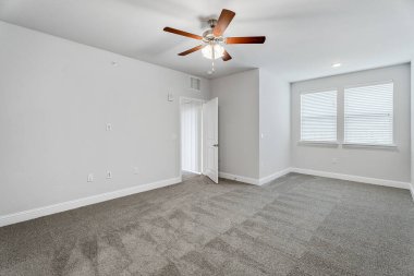 Boş ve mobilyasız yeni bir daire, beyaz duvarlı büyük boş bir yatak odası, büyük parlak pencereler. İçeride kimse yok. Kaliforniya, ABD - 2023