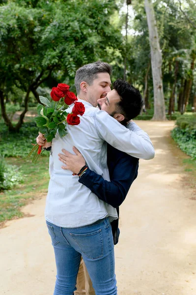 夏天的时候 年轻的男士们站在绿色的花园里 抱着一束玫瑰 亲吻着男朋友 — 图库照片