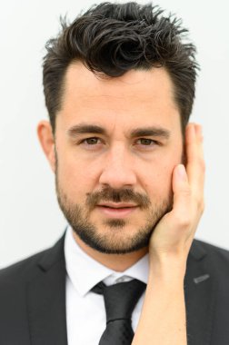 Omzundan kameraya bakan takım elbiseli yakışıklı sakallı adamın portresi.