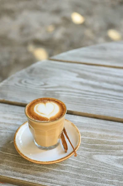 Cam bardakta yüksek açılı aromatik kahve ve vanilya çubuğuyla tabağa yerleştirilmiş kalp şeklinde latte.