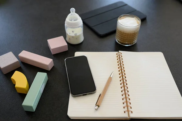 高角度的智能手机和笔记本 旁边放着笔和杯子咖啡 旁边放着玩具 桌上放着一瓶牛奶 — 图库照片