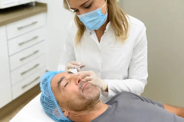 Female Dermatologist Medical Mask Giving Cosmetic Injection Forehead Male Patient — Stock Photo, Image