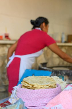 Önlükteki tanınmayan Meksikalı kadın aşçıya karşı leziz pişmiş chapati ekmeğinin seçici odak noktası mutfaktaki sıcak ızgaraya hamur koymak