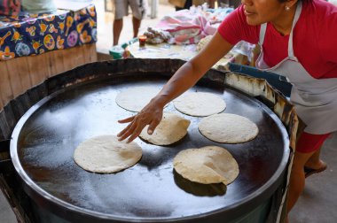 Tarlanın yukarısından tanınmayan Meksikalı kadın aşçı lezzetli chapati ekmeği pişirirken ızgaraya hamur koyar.