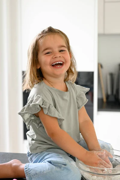 Θετικό Γελαστό Κοριτσάκι Casual Ρούχα Κάθεται Στο Τραπέζι Ανακατεύοντας Αλεύρι — Φωτογραφία Αρχείου
