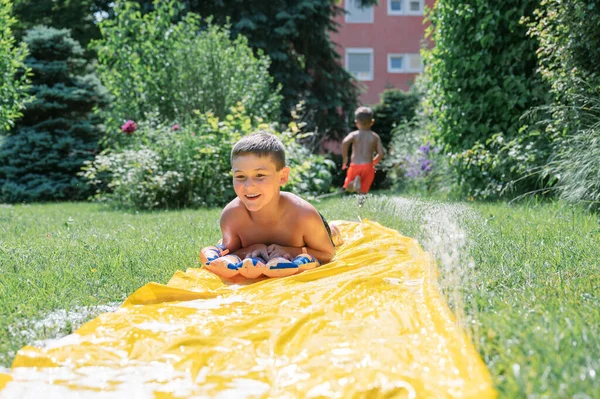 Chłopiec Bez Koszulki Ślizga Się Zjeżdżalni Mydła Ogrodzie Zabawy Śmiechu — Zdjęcie stockowe
