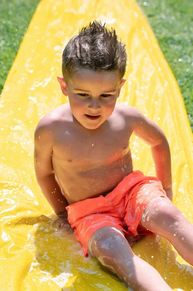 Wysoki Kąt Koszulek Chłopiec Siedzi Bawiąc Się Zjeżdżalni Wodnej Zabawy — Zdjęcie stockowe