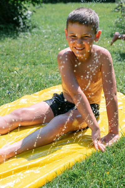 Widok Boku Wesoły Chłopiec Kąpielówkach Rozpryskiwanie Wody Podczas Siedzenia Kolorowe — Zdjęcie stockowe