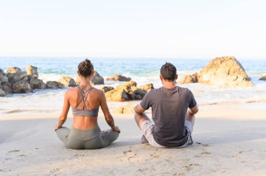 Spor kıyafetli kadın ve erkeğin güneşin doğuşunda kumlu sahilde poz verişlerinin arka görüntüsü. sağlıklı fitness içeriği