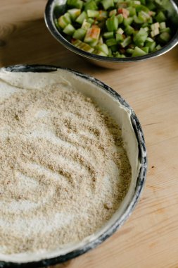Fırınlanmamış turta hamuru, fırın tavasında çoklu tahıl tozu ve güpegündüz ahşap masada bir araya getirilmiş taze kesilmiş yeşil ravent sapları.
