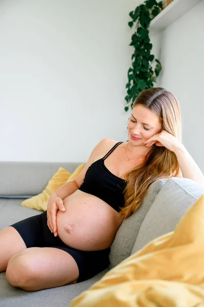 Front View Smiling Young Pregnant Female Black Sportswear Sitting Sofa — Stock Photo, Image