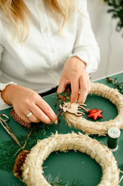 İsimsiz bir bayanın Noel çelengini kırmızı böğürtlenlerle süslemesi ve yeşil arka planda çelenk, farklı süslemeler, el işi eşyalar...