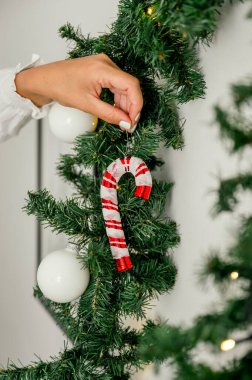 Tanınmayan Kafkas kadınlarının elleri Noel süslerini şık bir kıyafetle süslüyor, ağaca beyaz süsler takıyor, Noel süsü tutuyor. Noel ve yeni yıl konsepti