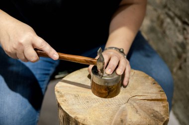 Atletizm atölyesinde çalışan, elinde tokmak tutan, mücevher tasarlayan tanınmamış bir kadının eli.