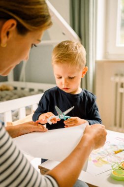 Küçük çocuk ve kız masada oturup evde vakit geçirirken oyuncaklarla oynuyorlar.