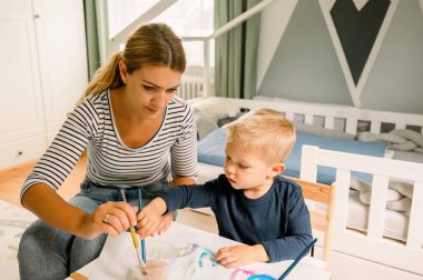 Sarışın, tatlı, sıradan görünümlü bir çocuk. Annesi evde oturuyor ve gündüz vakti boyalarla resim çiziyor.