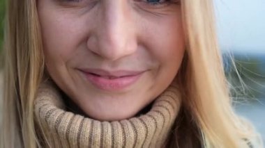 Kameranın arka planındaki göle ve ormana gülümseyen sarı saçlı neşeli genç bayanı yakından çek.