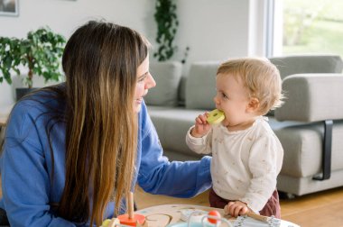 Anne ve kızı birlikte oynuyorlar, tahta oyuncakla müzik çalıyorlar. Anaokulu oyunları, çocukluk kavramı, daha önceki çocuk gelişimi, yaratıcılık, erken eğitim, arka plan oturma odası, rahat bir yer.