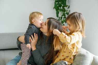 Samimi bir an, bir anneyi gülerken yakalar. Küçük kızı neşeyle yüzünü yalarken. Büyük kardeş eğlenceye, aile kavramına katılır.