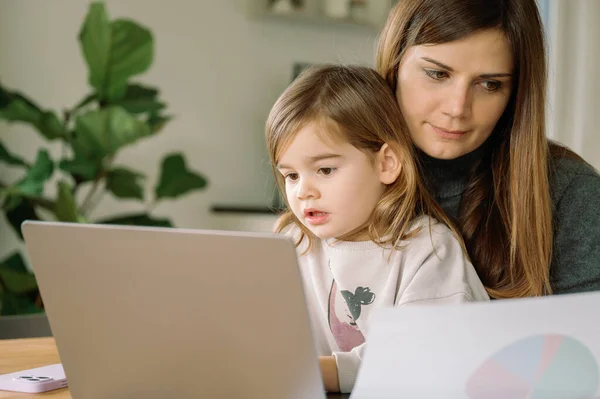 young working mother with daughter in home office