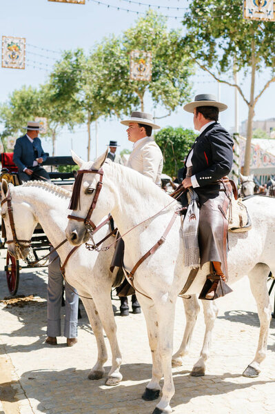 Мужчины в традиционной одежде верхом на лошадях и празднуют Севильскую апрельскую ярмарку, Севильскую ярмарку, Ферию Севильскую. Севильская апрельская ярмарка в Андалусии. Танцовщица фламенко