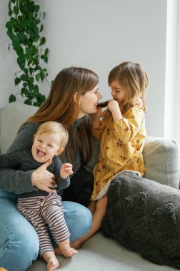 Genç bir anne küçük kızlarıyla evde vakit geçirir. Kahvaltı, annelik, aile kavramı. Yüksek kalite fotoğraf