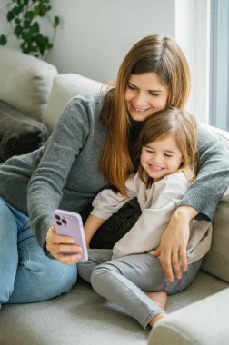 Neşeli anne ve küçük kızı video görüşmesi yapıyor, dedelerini selamlıyor, doğum günü için babalarını selamlıyor, selfie çekiyor, eğleniyor, eğleniyor, rahatlıyor. annelik, ebeveynlik kavramı