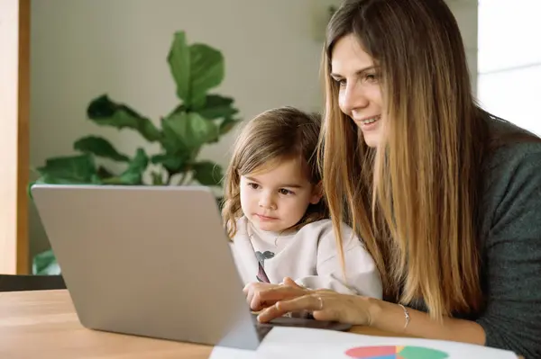 young working mother with daughter in home office