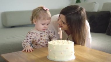 Birinci yaş günü pastası, süslemeli ve minimalist dekorasyonlu. Arka plandaki oturma odasında, bir numaralı mumla birlikte. çocukluk kavramı