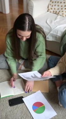 Odaklanmış genç bir kadın, arkadaşıyla birlikte bir belgeyi gözden geçirir. İkisi de koltuğun önünde rahatça otururlar. Bitkilerle samimi bir arka plan, yumuşak ışık, Budapeşte 'de bir daire