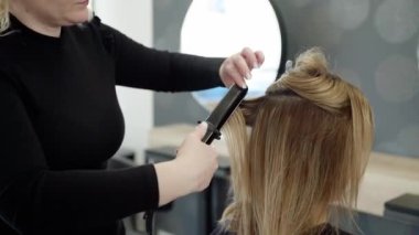 Ağır çekim. Kafkasyalı genç bir kadın kuaförde saçını yaptırıyor. Kuaförde saç tarama, boya, çamaşır, saç kurutma ve saç şekillendirme. Güzellik salonu konsepti. 4k görüntü
