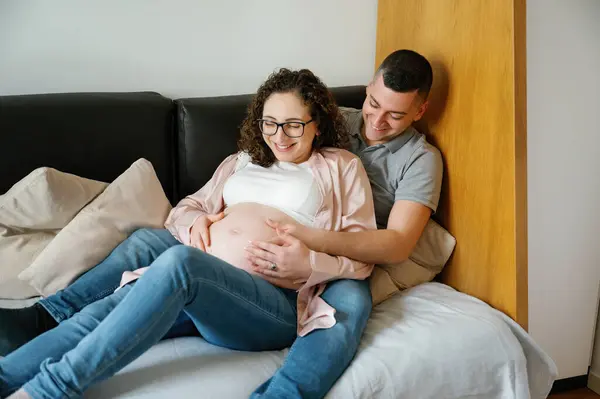 Curiosa Pareja Embarazada Manos Vientre Acostado Sofá Sonriendo Juntos — Foto de Stock