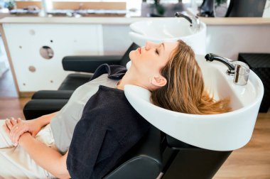 Bir güzellik salonunda saçını yıkatan çekici genç bir kadının yan görüntüsü. güzellik ve saç bakım konsepti