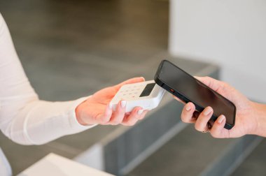 Kadın el ele tutuşuyor, kart okuyucu yok, müşteri cep telefonu faturasıyla ödeme yapıyor, dükkanda, kafede, güzellik salonunda. iş kavramı