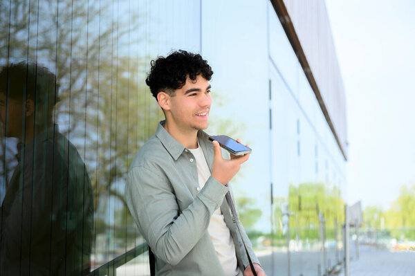 Портрет стильного веселого молодого человека в повседневной одежде, разговаривающего по смартфону на улице, отворачивающегося. люди концепция