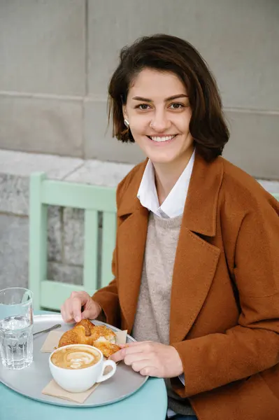Вертикальное Фото Улыбающейся Женщины Завтракающей Круассаном Кофе Кафетерии Тротуаре Стоковая Картинка
