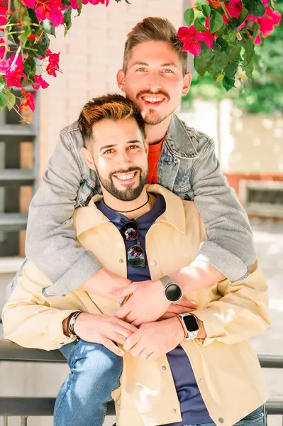 Güneşli bir günde Avrupa 'da seyahat ederken, tesadüfi giysiler içinde, kucaklaşan ve kameraya bakan mutlu, yakışıklı eşcinsel çift. LGBTQ, gurur ayı konsepti
