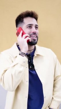 Mutlu genç homoseksüel adam dışarıda duruyor, bir telefon görüşmesi yapıyor, akıllı telefonla konuşuyor, dişlek gülümsemeli, pozitif, çeşitlilik, eşitlik. LGBTQ ve insanlar konsepti