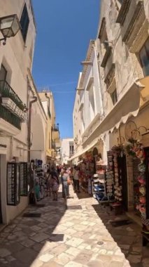 İnsanlar ve turistler güneşli bir günde Otranto, Salento, Güney İtalya 'da dar sokaklarda yürüyorlar