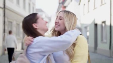 Kafkasyalı güzel, uzun sarı ve esmer saçlı, günlük giysiler içinde Avrupa 'da bir yaya caddesinde yürüyen bir şehirde konuşan ve gülümseyen iki kadın. yaşam tarzı konsepti