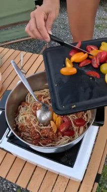 Kamp alanında açık hava yemekleri. Tanımlanamayan beyaz bir kadının eli karavanın dışında öğle yemeği hazırlıyor ve yemek pişiriyor. Yaşam tarzı ve tatil konsepti