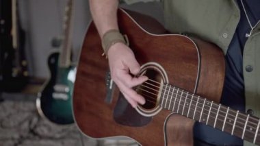 Erkek gitarist günlük kıyafetlerle stüdyoda oturuyor, akustik gitarla müzik çalıyor, rock müzik kaydediyor. müzik ve yaşam tarzı kavramı
