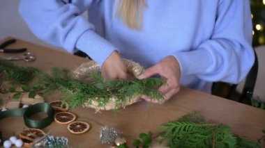 Tanınmayan kadın elleri Noel çelengi yapıyor, aralık ayında süsleme yapıyor, Noel çelengi, Noel ve tatil konsepti.