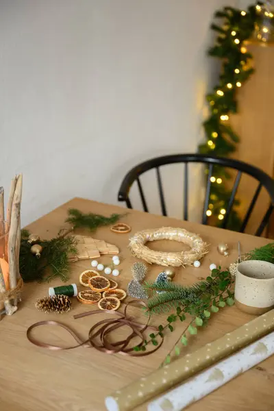 Çam dalları, kurutulmuş portakallar ve Noel çelengi yapmak için hazırlanmış kurdelelerle dolu bir el işi masası. Noel ve zanaat konsepti